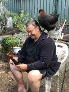 Cheepie our Pet Chicken sitting on papas shoulder while he is reading. Article is about How Long Do Chickens' Live?