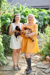 Two teenage girls holding chickens