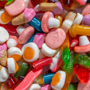 A collection of various colorful candies, including gummy worms, egg-shaped jelly candies, and assorted sweets, not suitable as food for chickens."